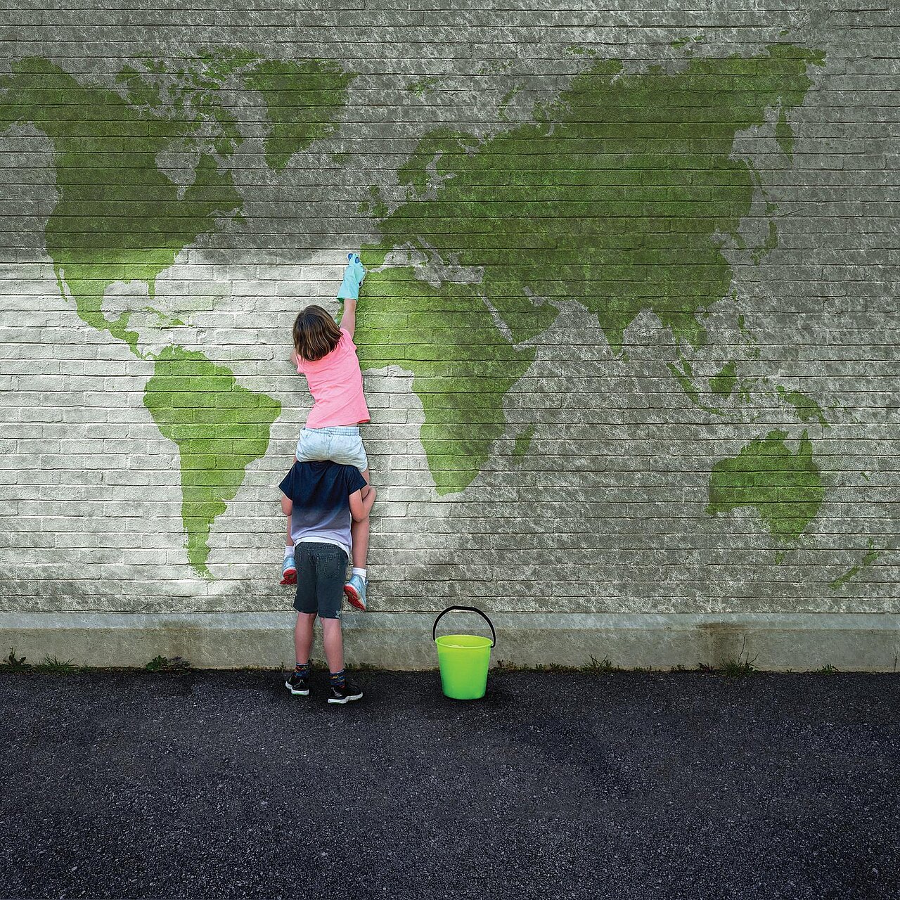 Kinder machen eine Räuberleiter und bemalen eine Wand