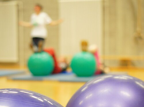 Menschen in einem Bewegungskurs mit großen Gymnastikbällen